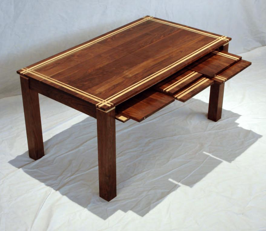 Walnut dining table with maple inlays with expanding panels.