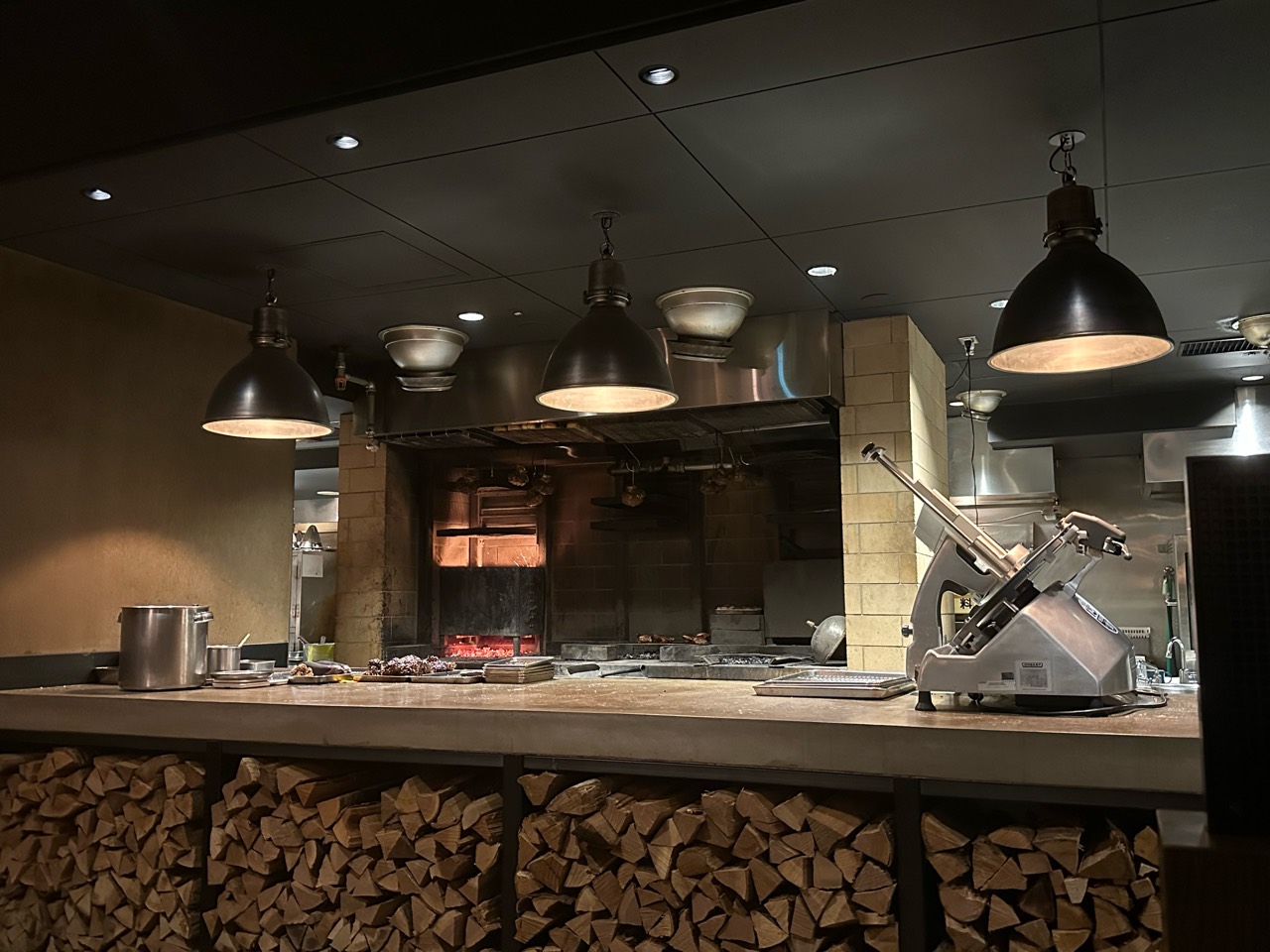 SMOKE DOOR's open kitchen, with stacked firewood beneath the counter