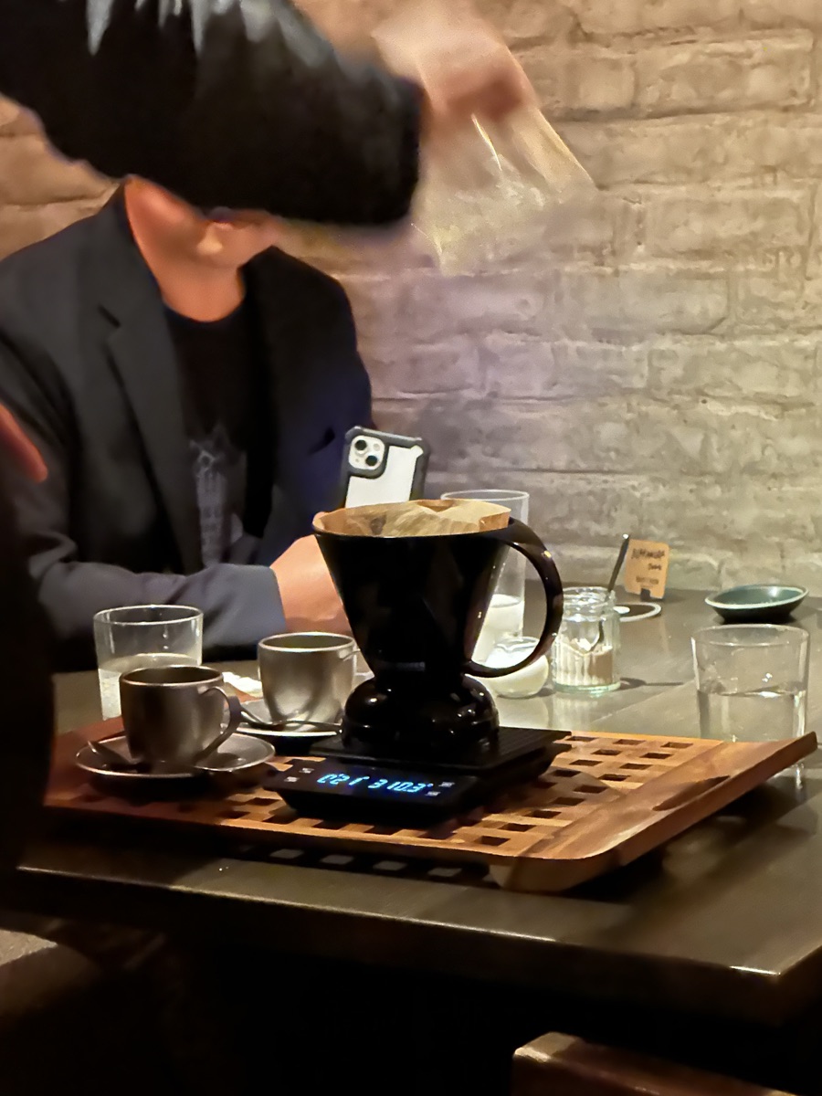 Coffee being brewed at the table on a wooden tray
