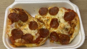 Naan pizza topped with pepperoni in a takeaway style container.