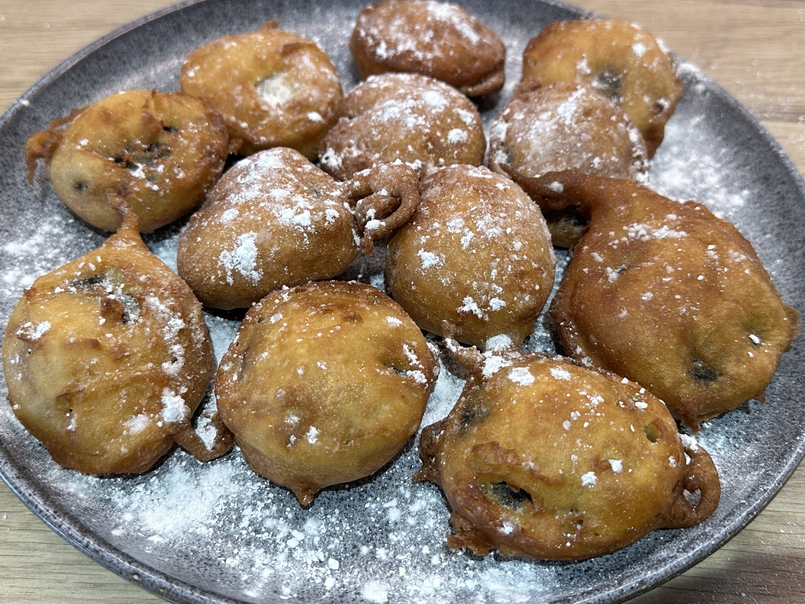 Deep fried cookies & cream biscuits dusted with icing sugar on a serving plate.