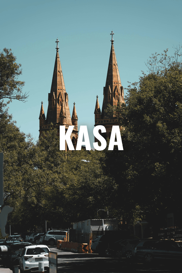 A church with two tall, pointed spires rising above trees, with a parking lot filled with cars in the foreground, and the word 'KASA' overlayed in bold text.