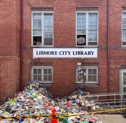 A photo showing a pile of soggy books being thrown from the windows of Lismore City Library