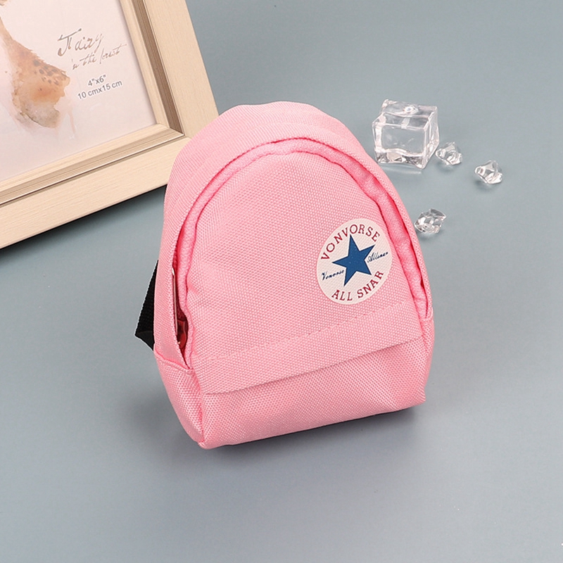Pink mini canvas backpack keychain with white circular logo.