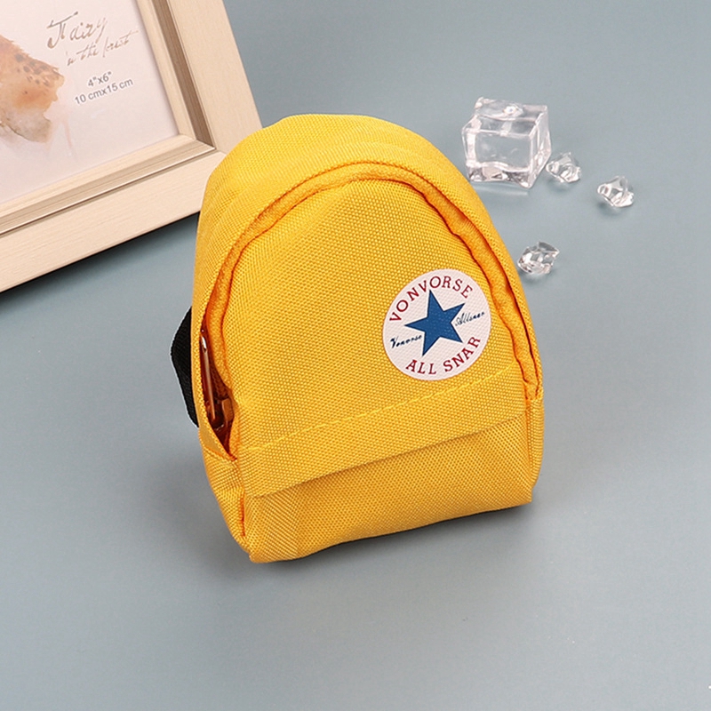 Yellow mini canvas backpack keychain with white circular logo.