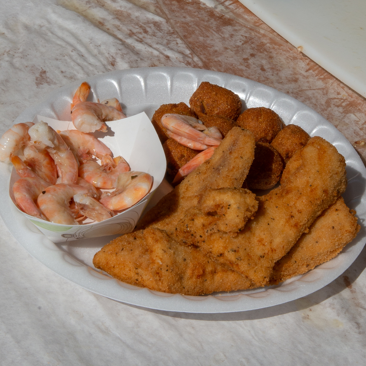 Locals, visitors devour the seafood - A plate of food on a table - Pakora