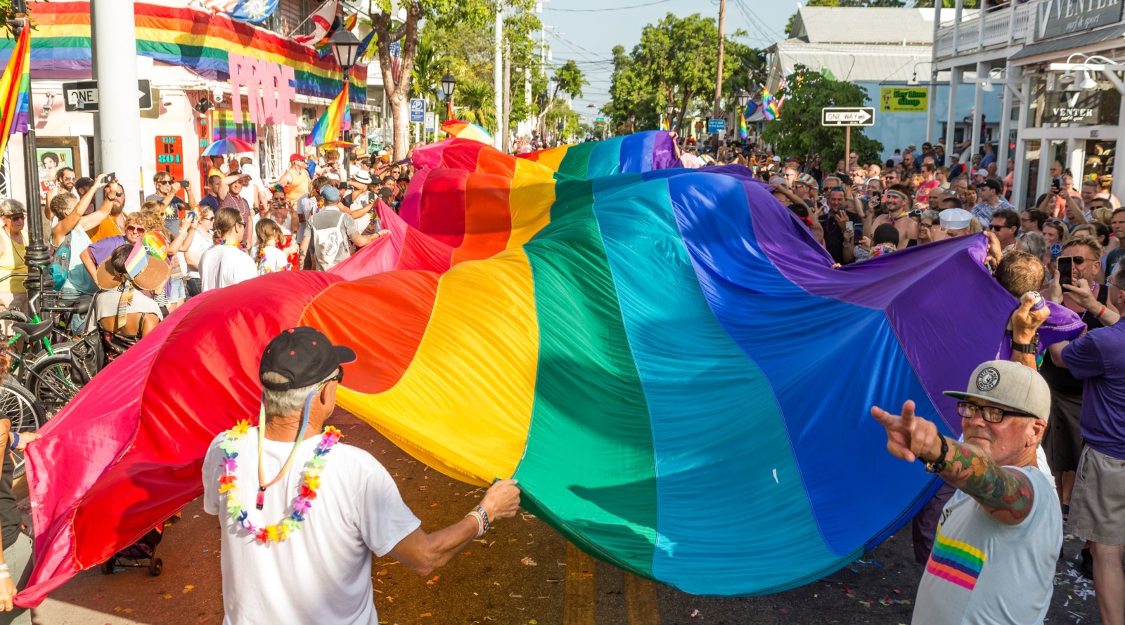 a man holding a rainbow colored kite in front of a crowd
