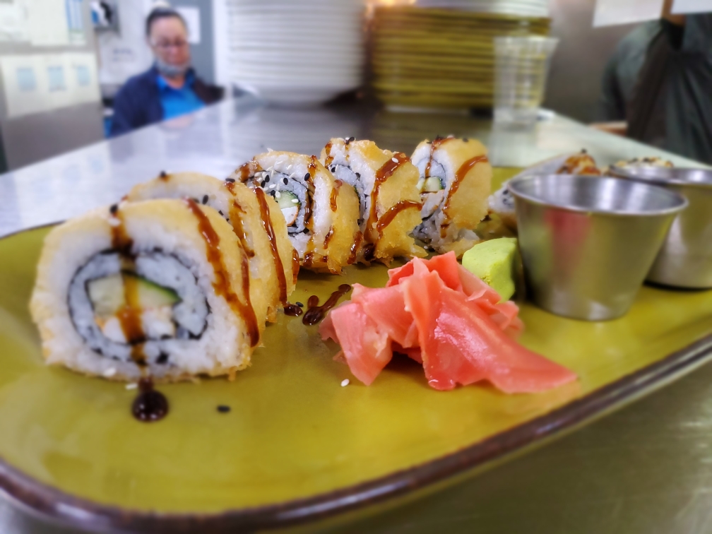 a plate of sushi on a table with a person in the background