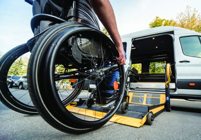 A man in a wheelchair moves to the lift of a specialized vehicle a man in a wheelchair is loading a van