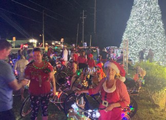 IN PICTURES: LIGHTED BIKES RIDE THROUGH KEY LARGO FOR CHARITY a group of people standing around a christmas tree