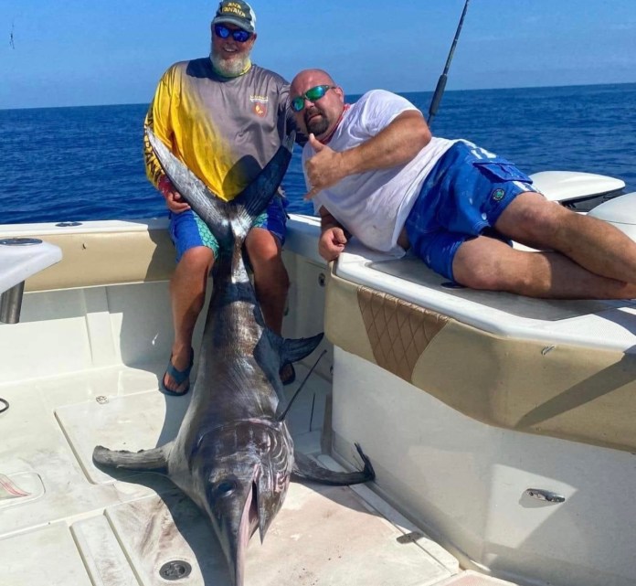 swordfish a man sitting on a boat holding a fish