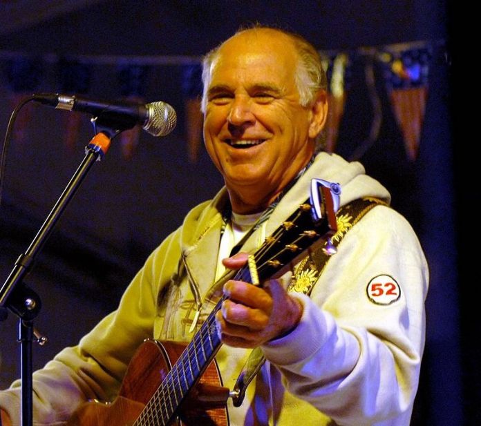 buffett a man playing a guitar and singing into a microphone