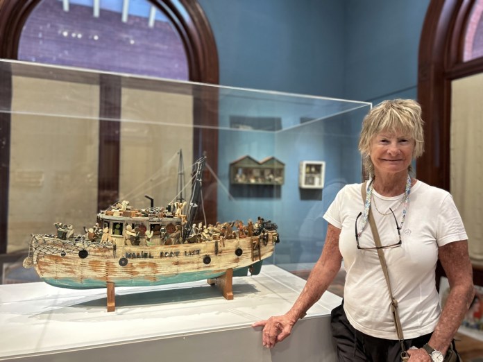 2 Large a woman standing next to a model of a boat
