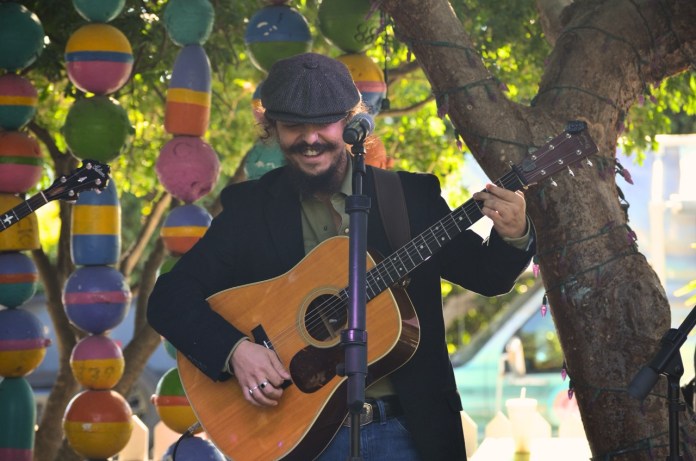 a man playing a guitar under a tree