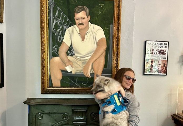 a woman holding a cat in front of a painting