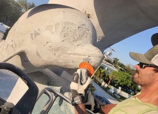 ICONIC DRC DOLPHIN STATUE GETS A FULL FACELIFT FROM ARTIST RYAN KEMPPAINEN a man sitting in a truck working on a sculpture