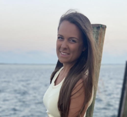 a beautiful young woman standing next to a wooden pole