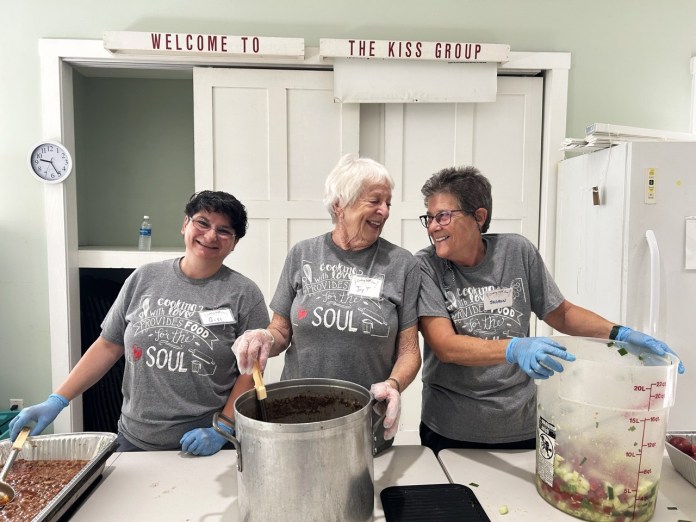 a group of people standing around a pot of food