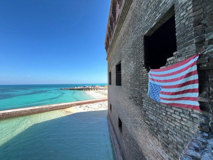 upside down flag Large an american flag hanging on a brick wall near the ocean