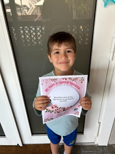 a young boy holding up a paper sign