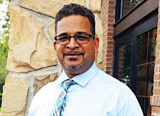 a man in a dress shirt and tie standing in front of a building