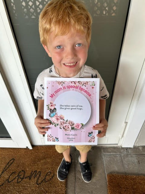 a young boy holding up a picture of himself