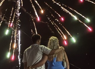 BON VOYAGE & A BLESSING: KEYS FISHERIES HERALDS THE ARRIVAL OF LOBSTER SEASON a man and a woman standing in front of a firework display