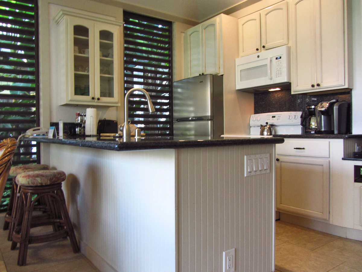View of kitchen showing peninsula with countertop overhang making a bar top for short bar stools.