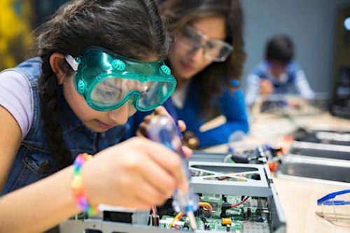 Mother watching daughter assembling electronics at science center