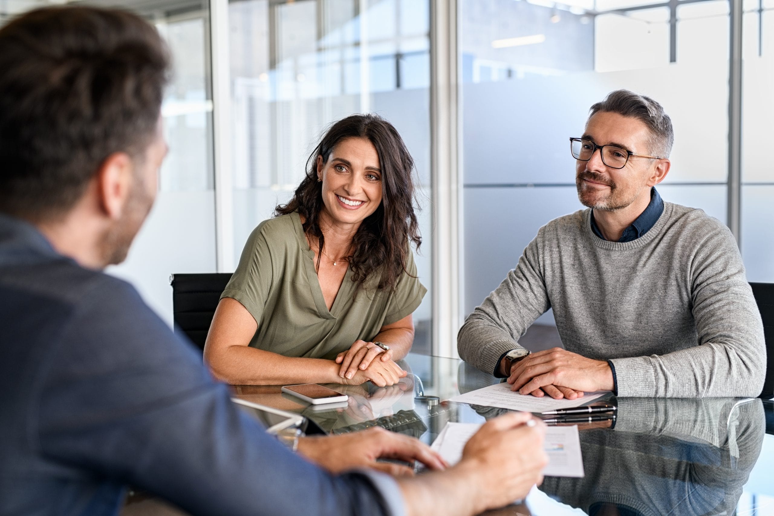 A couple meeting with a construction consultant at a modern office table, reviewing plans and discussing a project.