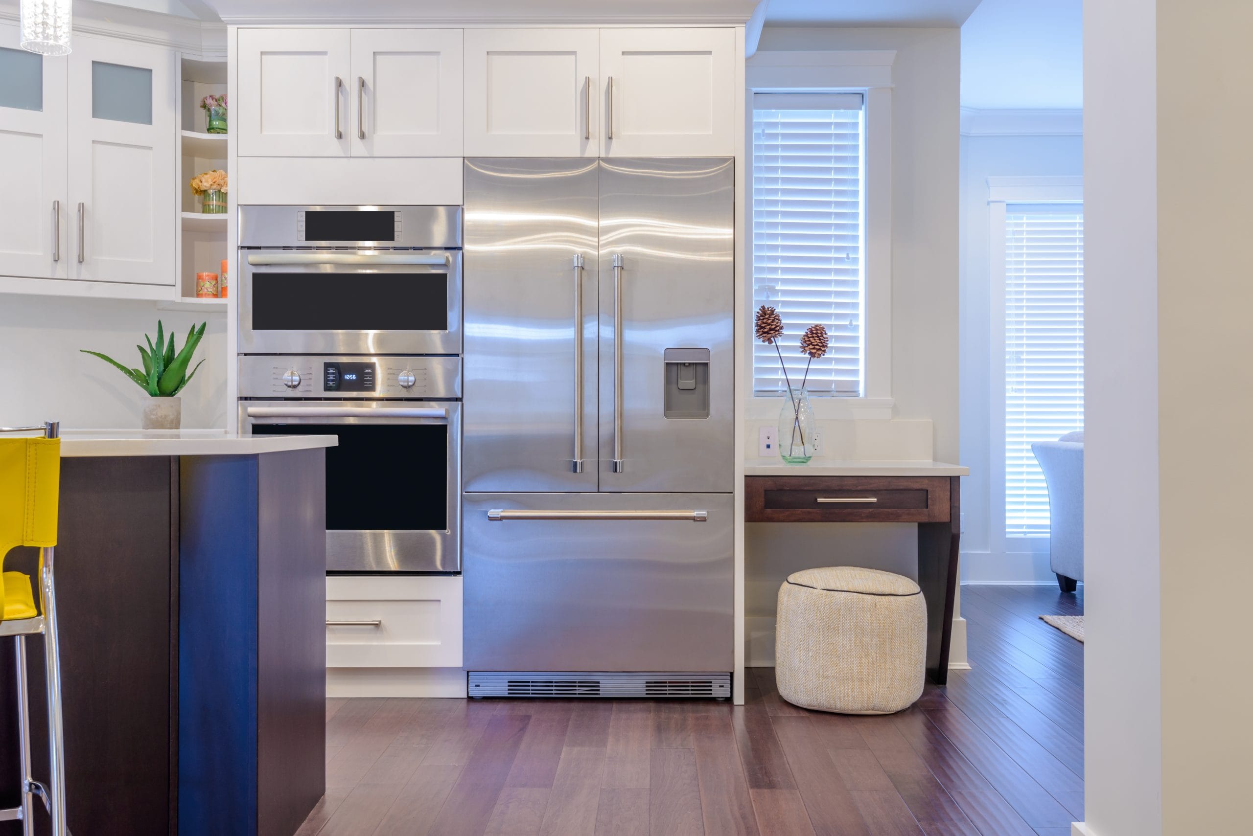 Modern kitchen interior with stainless steel appliances, white cabinetry, and bright natural lighting in a luxury home.