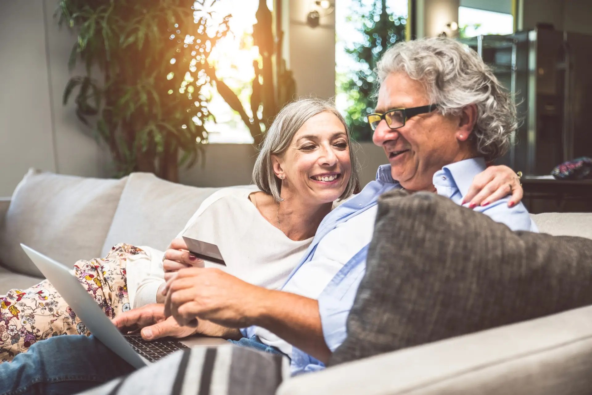 Senior couple smiling while reviewing and signing a digital contract on a laptop, completing online payment.