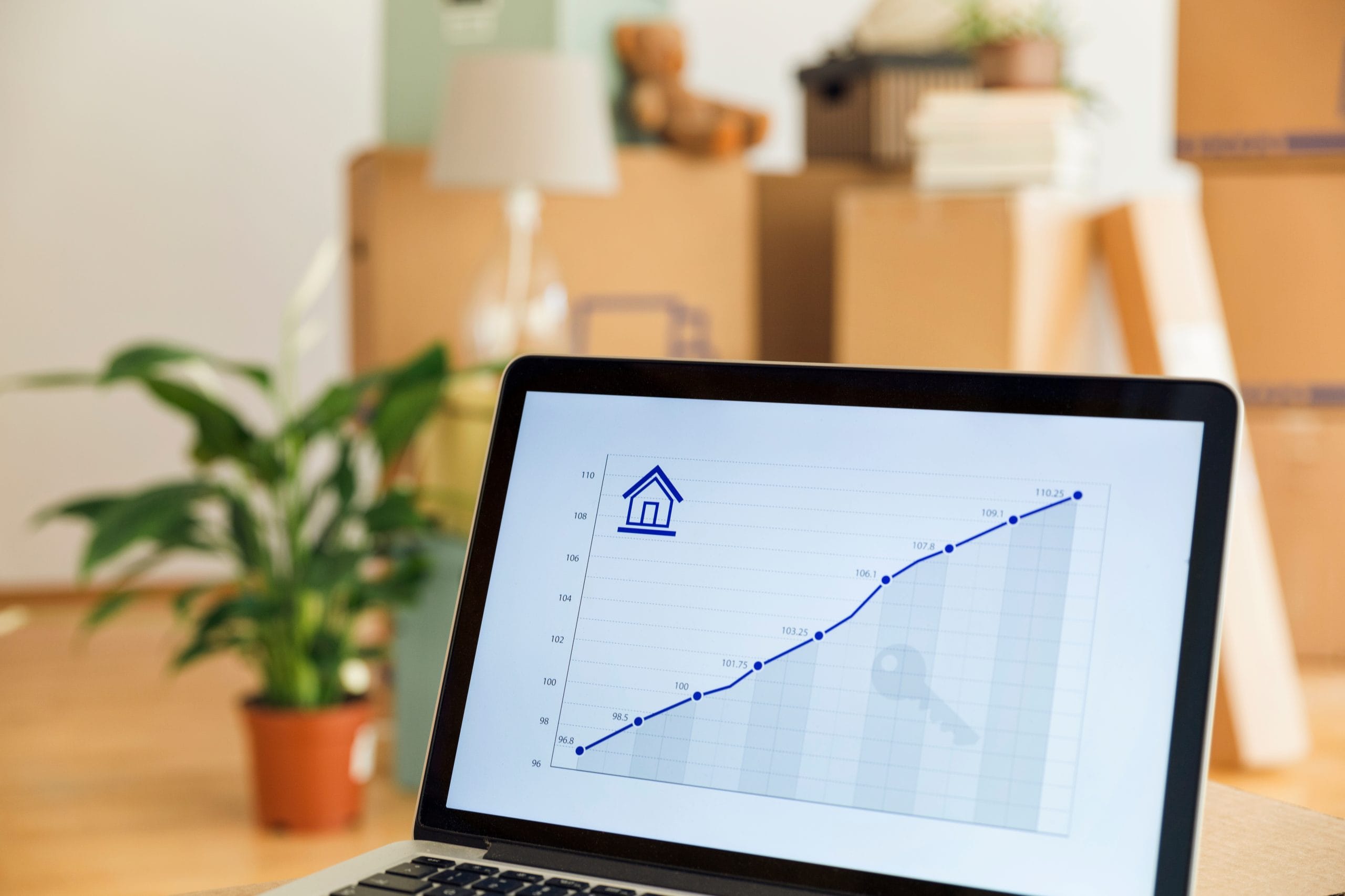 Laptop screen showing a line graph with a house icon, symbolizing financial growth and progress invoicing.