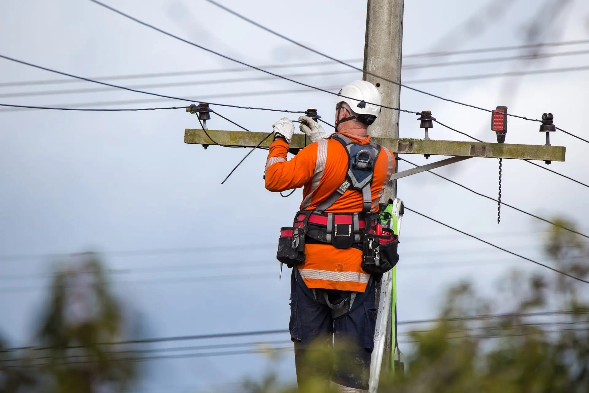 Lineman in safety gear installing electrical power lines to a newly constructed residential home