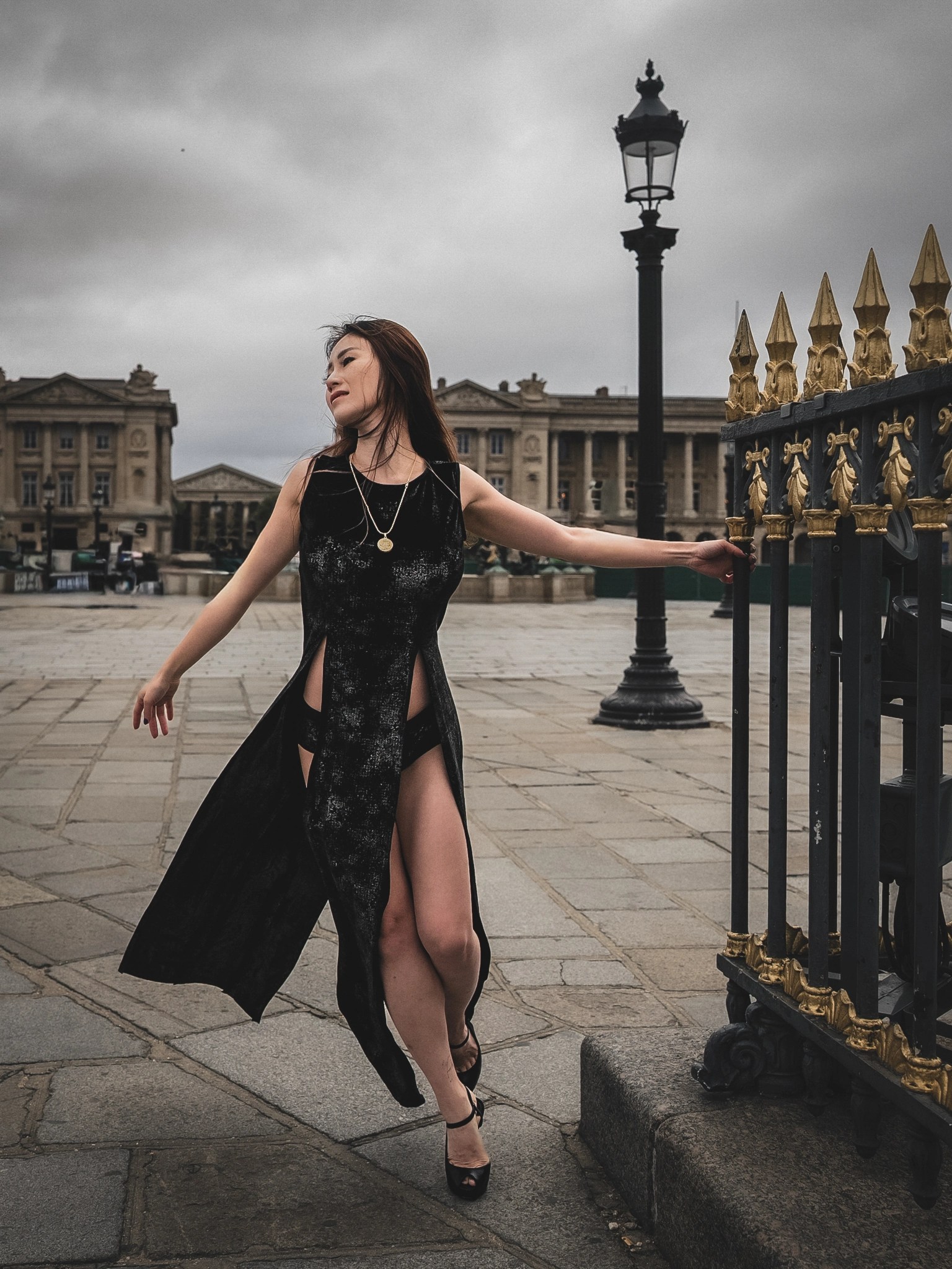 Lily Stadil walks with her arms extended in a black BRAXTON dress at Place de la Concorde