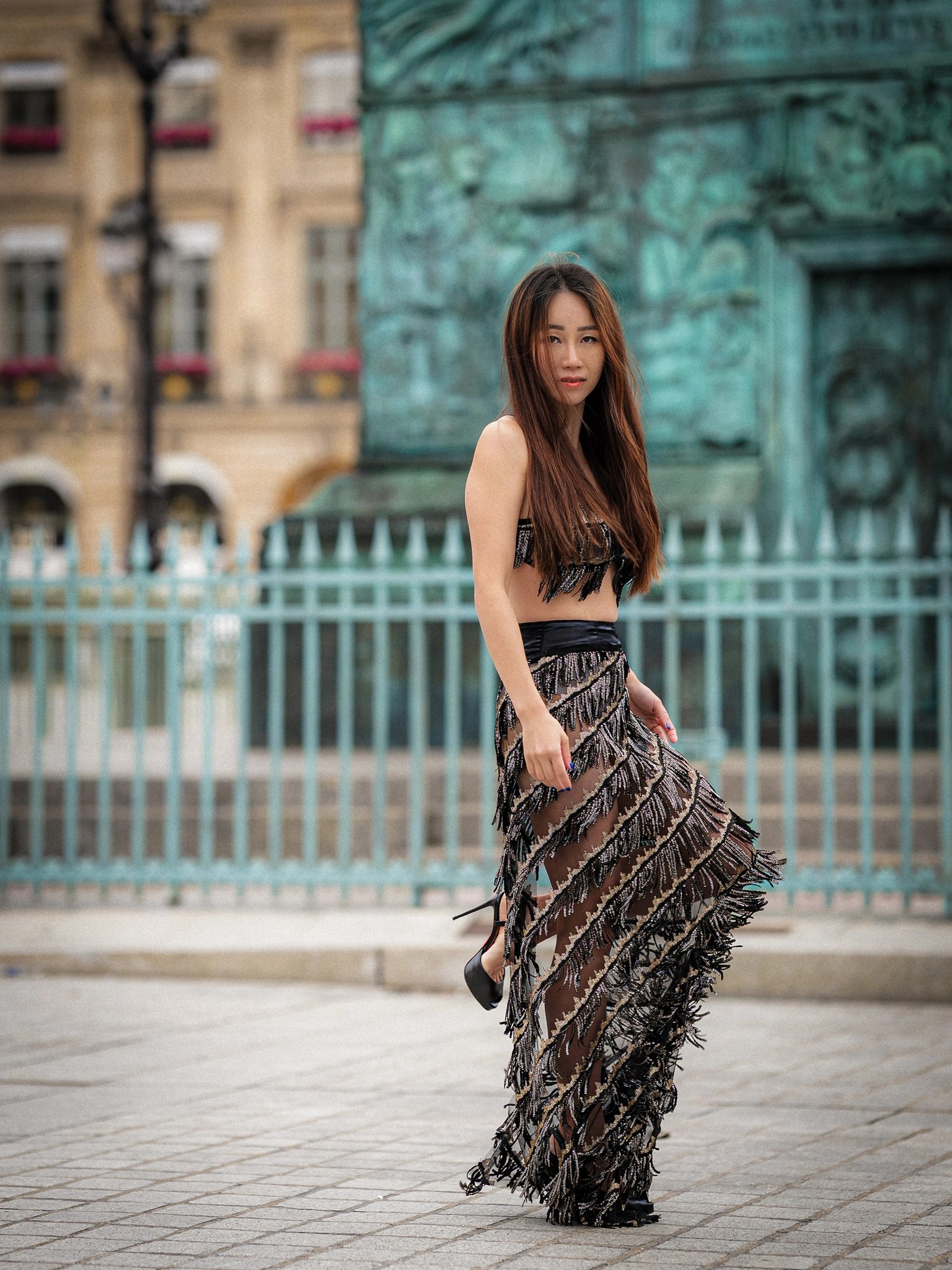 Lily Stadil stands beside the turquoise base of the Vendôme Column