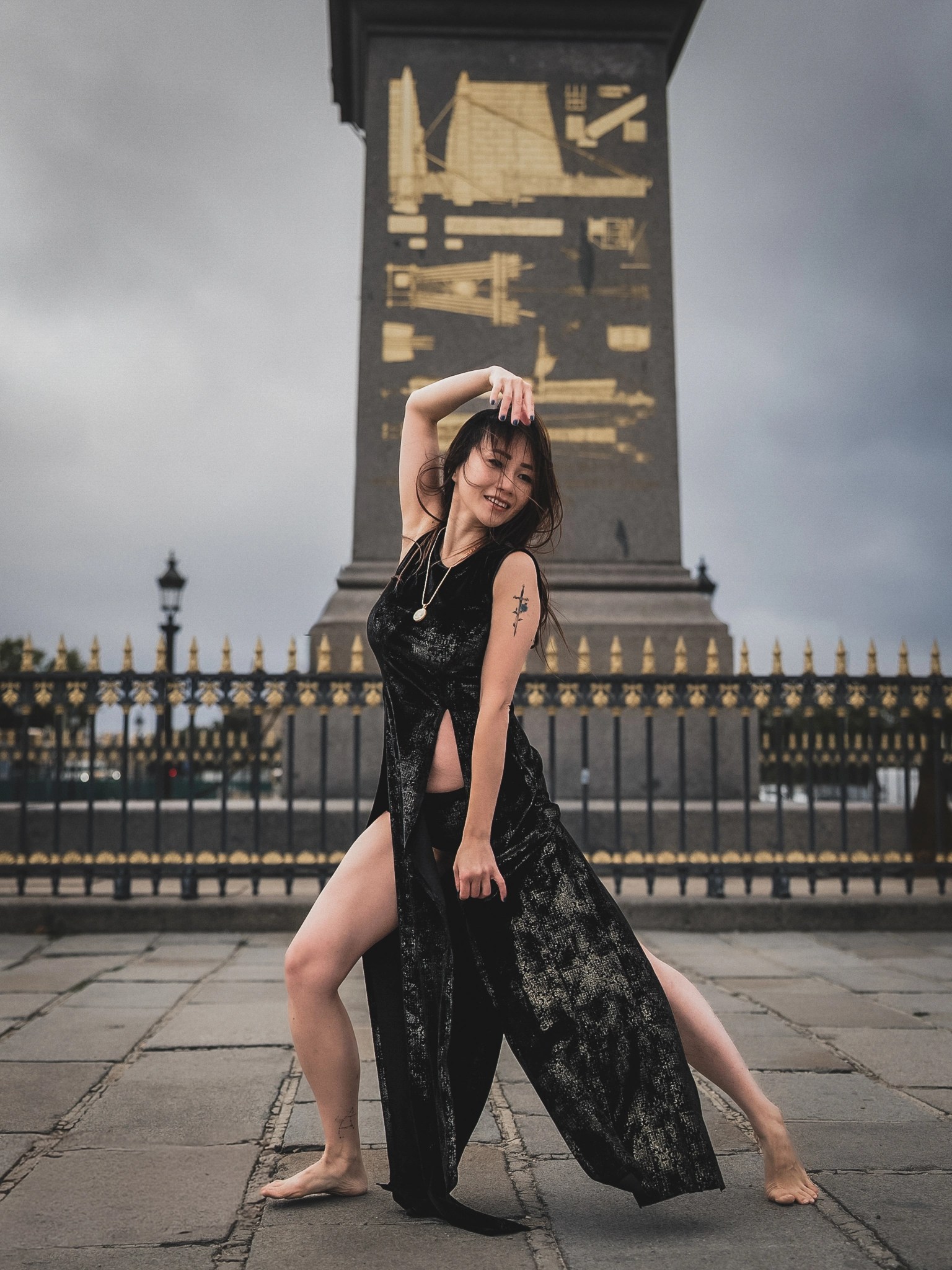 Lily Stadil poses barefoot with one arm overhead at Place de la Concorde