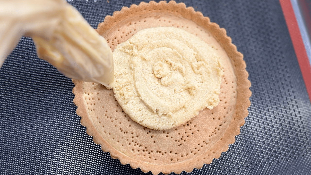 piping frangepane cream on the tart shell