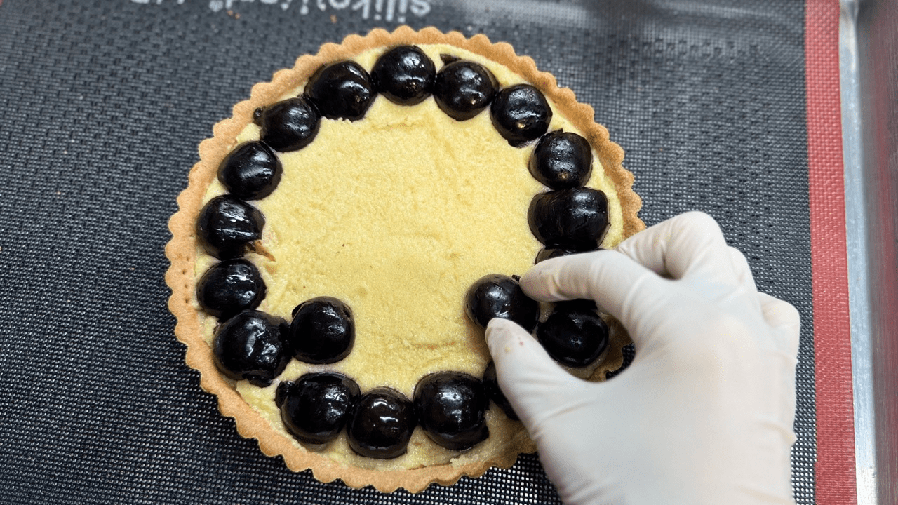 adding cream and cherry into the frangepane tart