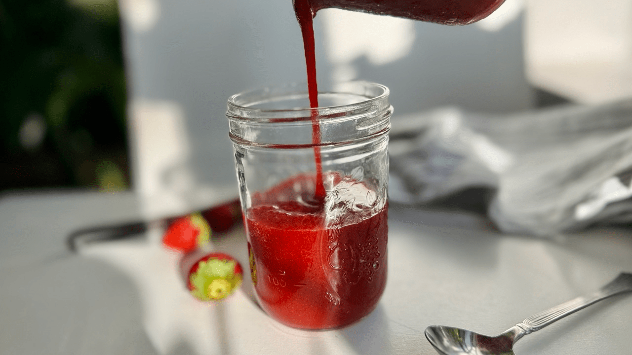 pouring strawberry sauce into jar
