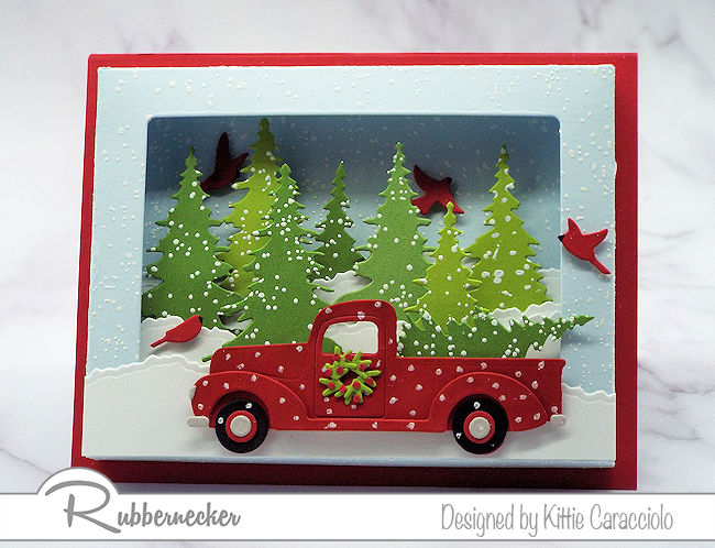 As adorable card featuring die cut trees and a cute pickup truck all set into a card made using a shadow box card die
