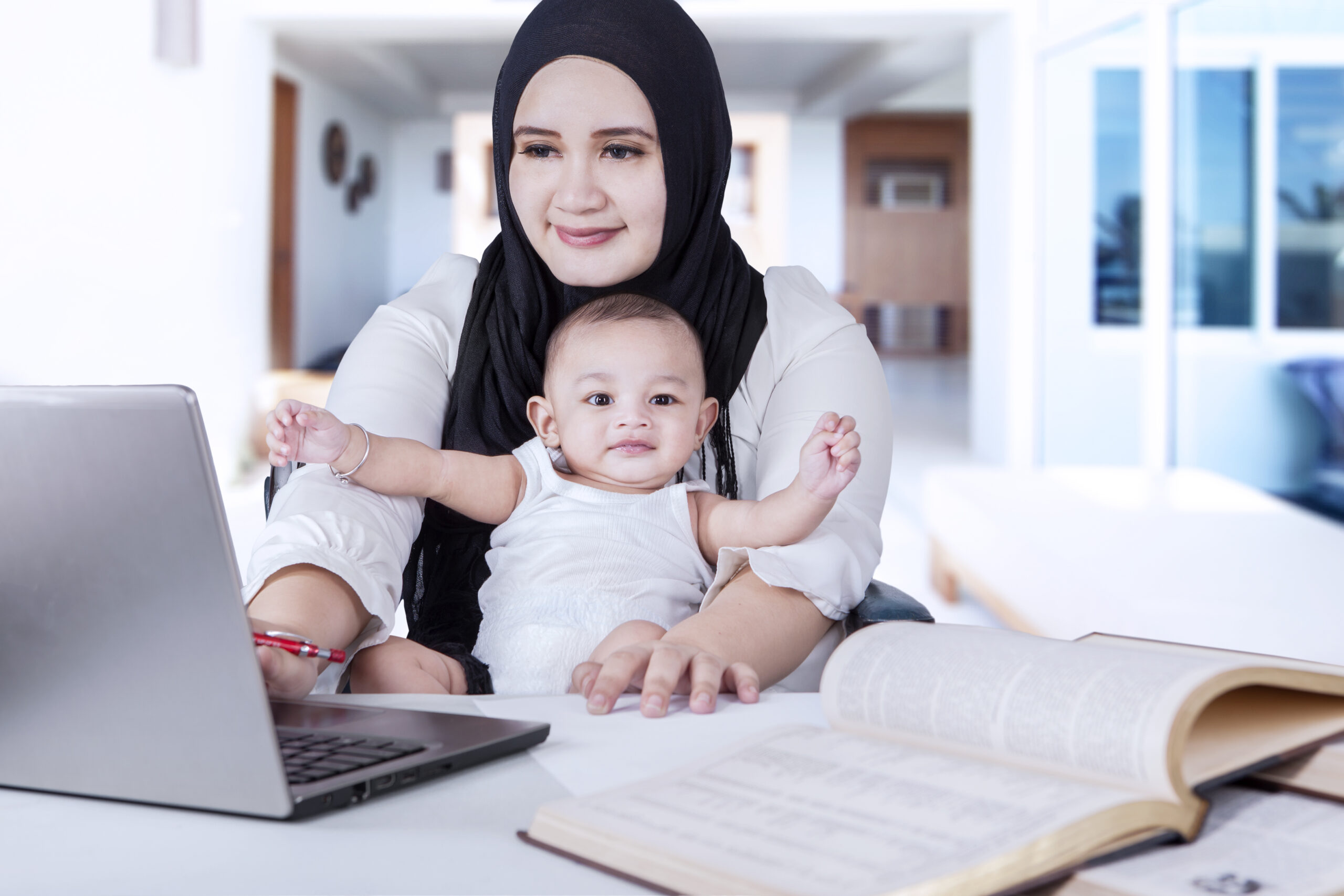 Young,Mother,And,Her,Baby,Using,Laptop,To,Work,From