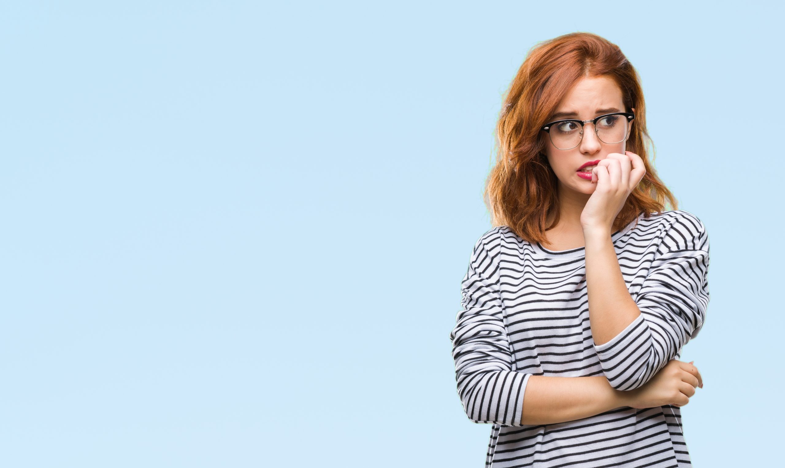 Young beautiful woman over isolated background wearing glasses looking stressed and nervous with hands on mouth biting nails. Anxiety problem.