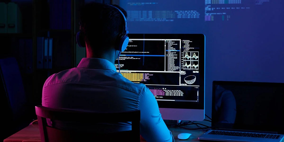 Developer working on code late at night, view from the back