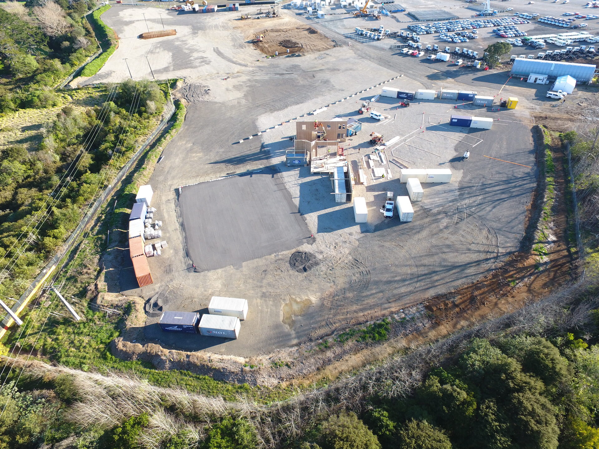 Aerial overview of a fenced production backlot with containers and sets
