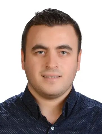 Bir erkeğin, koyu mavi desenli bir gömlekle poz verdiği profesyonel bir portre.