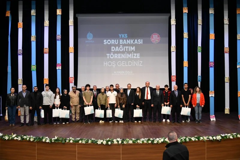 YKS Soru Bankası Dağıtım Töreni'nde öğrenci ve yetkililerle birlikte sahnede poz veren grup fotoğrafı.