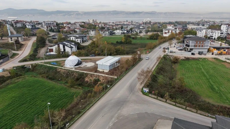 Hava fotoğrafı, Kocaeli'de inşaat halinde olan Gün Evi ve Kadın El Emeği Mağazası'nın çevresini gösteriyor. Etrafında yeşil alanlar ve yerleşim yerleri bulunuyor.