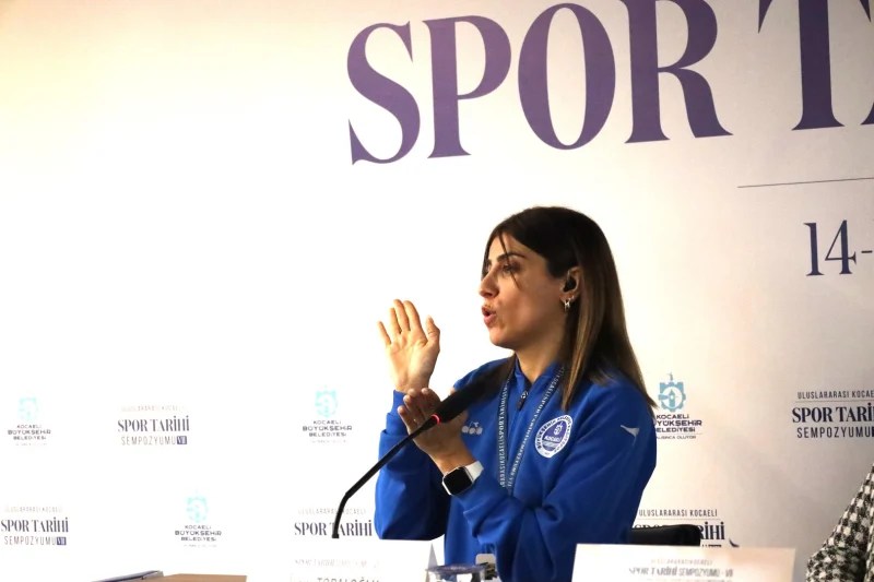 Bir kadın sporcu, Kocaeli Spor Tarihi Sempozyumu'nda deneyimlerini paylaşırken konuşma yapıyor.