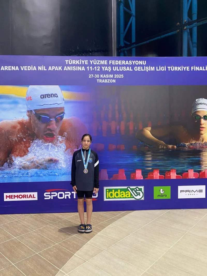 Çayırova Belediyesi Eğitim Spor Kulübü sporcusu Yağmur Yeyin, Trabzon'daki yüzme şampiyonasında madalya kazanırken, arka planda yüzme temalı bir afiş bulunmaktadır.